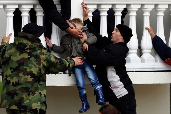 Сербские солдаты армии эвакуируют мальчика из затопленного дома в городе Оберновац