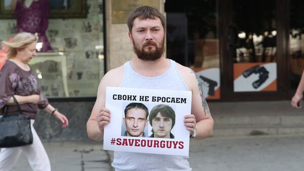 Мужчина держит плакат с фото задержанных на Украине журналистов телеканала Лайф Ньюз Олега Сидякина и Марата Сайченко. Архивное фото