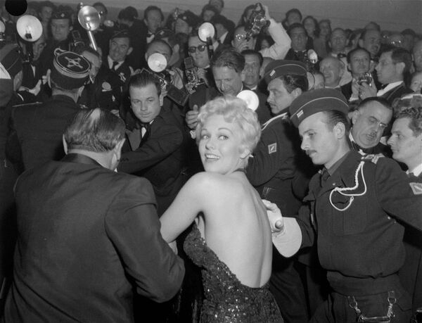 Фестивальная бомба Ким Новак пытается пройти сквозь толпу фотографов на Каннском кинофестивале, 25 апреля 1956 года