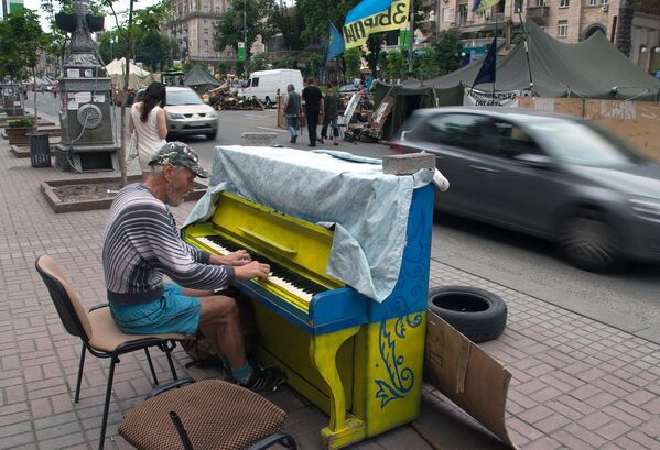 Мужчина играет на фортепиано напротив палаточного лагеря на улице Крещатик в Киеве