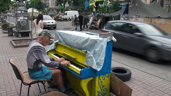 Мужчина играет на фортепиано в палаточном лагере на улице Крещатик в Киеве