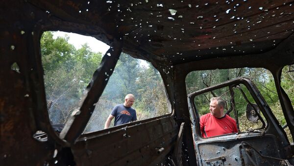 Жители города Рубежное осматривают обстрелянный и сгоревший автомобиль, архивное фото