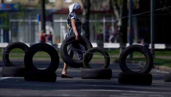 Женщина несет автомобильную шину на КПП, расположенный на дороге в аэропорт Донецка. 27 мая 2014