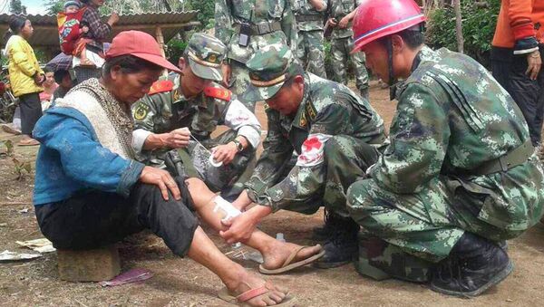 Военные оказывают помощь женщине, пострадавшей в результате землетрясения в Китае