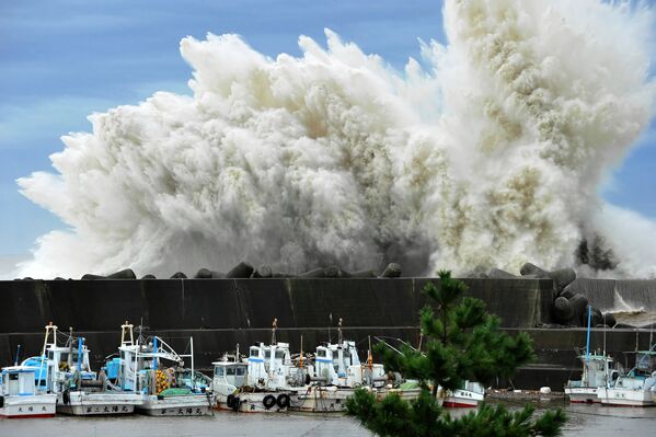 Бушующие волны ударяют против волнореза в портовом городе Кихо, Япония