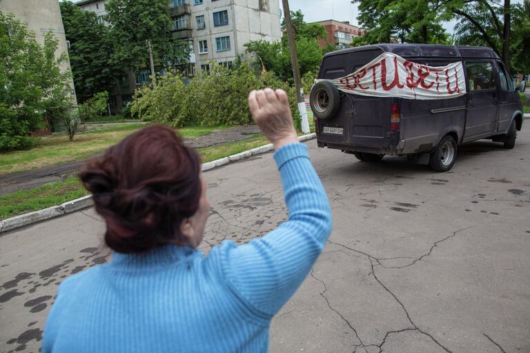 Женщина провожает детей. Жители города Славянска, который подвергается обстрелам украинскими силовиками, эвакуируют детей из города