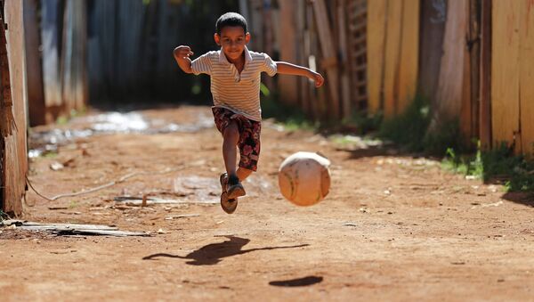 Мальчик играет в футбол в трущобах города Бразилиа. Архивное фото