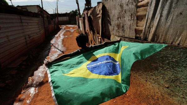 Мальчик с бразильским национальным флагом в трущобах города Бразилиа