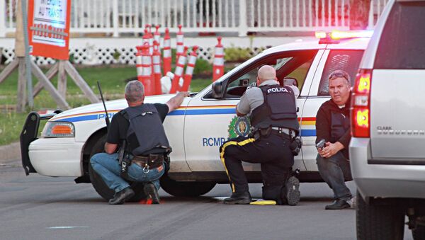 Полицейские на позициях за служебными машинами в городе Монктон, провинция Нью-Брансуик, Канада