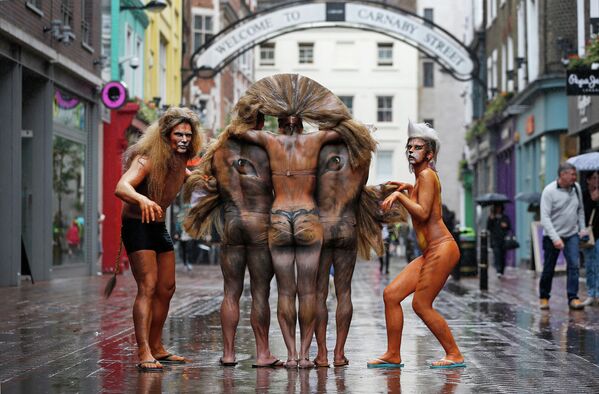 Модели с нарисованным на телах изображением головы льва позируют для фотографов в центре Лондона