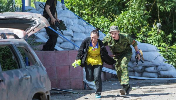 Боец народного ополчения сопровождает местную жительницу в укрытие во время танковой атаки украинской армии поселка Семеновка