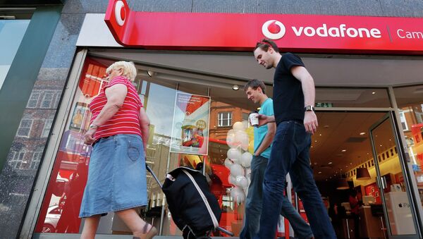 Жители проходит мимо магазина Vodafone в Лондоне