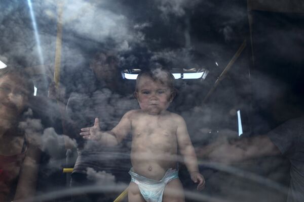 Ребенок в салоне автобуса, стоящего в очереди к границе. 20 июня 2014, пограничный пункт Изварино, Луганская область