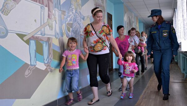 Сотрудница МЧС РФ помогает беженкам из Луганской области с детьми разместиться