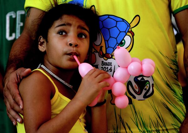 Девочка смотрит футбольный матч на большом экране в городе Манаус, Бразилия