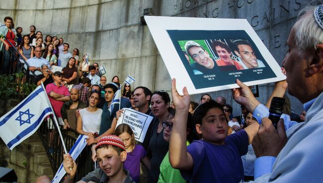 Ребенок держит портреты похищенных еврейских подростков.