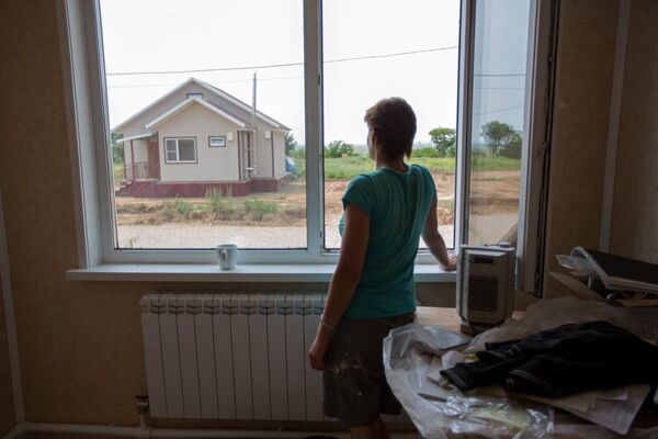 Рабочий-маляр смотрит на дом, построенный в рамках проекта Первого канала Всем миром
