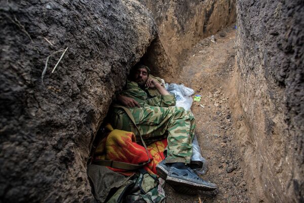 Ополченец отдыхает в траншее на передовой позиции в поселке Семеновка