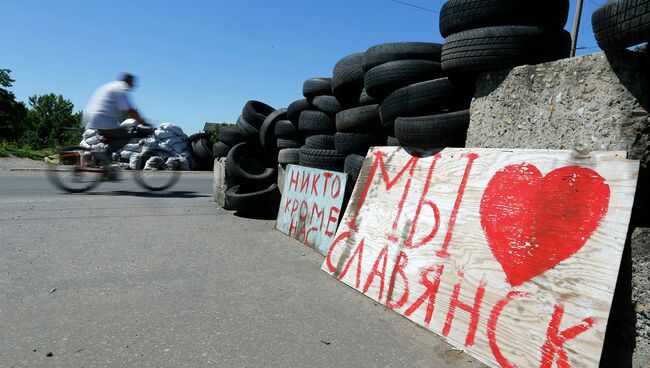 Человек едет на велосипеде мимо КПП в украинском городе Славянск