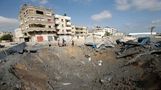 Палестинцы рядом с кратером образовавшемся в результате удара с воздуха Израильской армией. Архивное фото