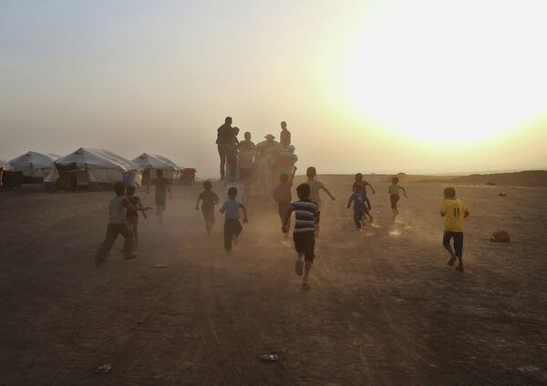 Дети бегут за грузовиком в лагере для беженцев на севере Ирака