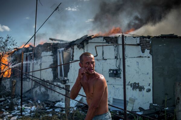 Местный житель во время тушения пожара в одном из домов в станице Луганская, подвегшейся авиационному удару вооруженных сил Украины.