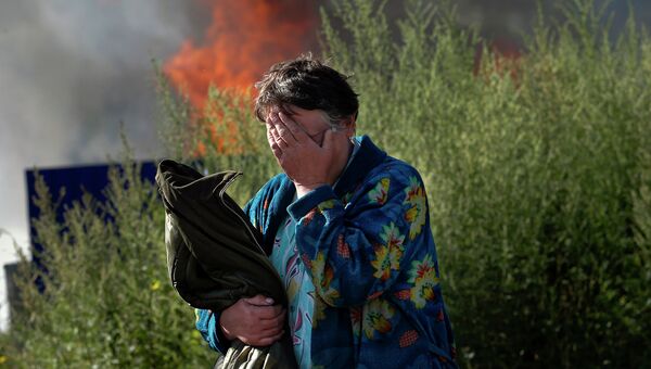 Женщина плачет возле своего горящего дома в Славянске