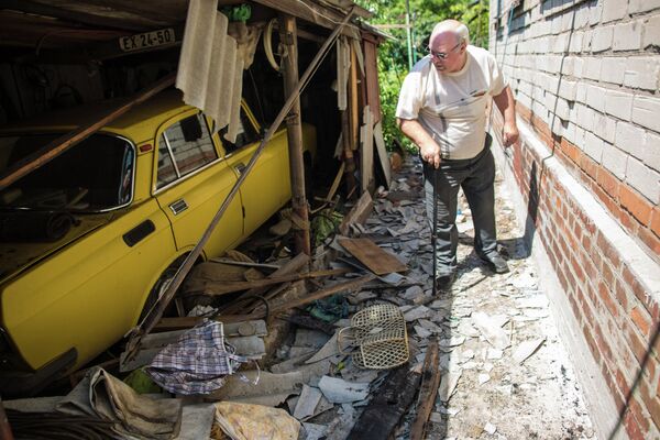 Житель Славянска у разбитого в результате артиллерийского обстрела автомобиля