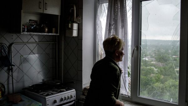 Женщина у окна с выбитыми стеклами в одной из квартир в пострадавшем от минометного обстрела украинскими силовиками жилом многоквартирном доме. Архивное фото