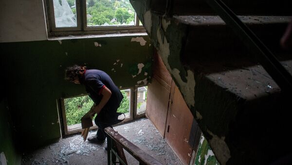 Женщина убирает осколки стекол на лестнице в пострадавшем от минометного обстрела украинскими силовиками жилом многоквартирном доме в Луганске