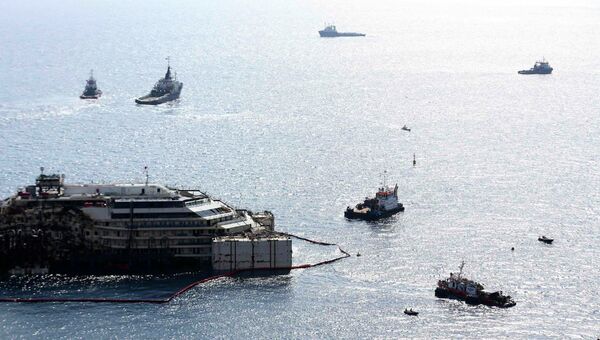 Круизный лайнер Коста Конкордия в окружении буксиров во время перемещения в порт Генуи