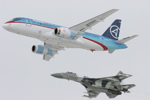 Самолет Sukhoi SuperJet-100 (вверху) в сопровождении истребителя Су-35 (внизу)