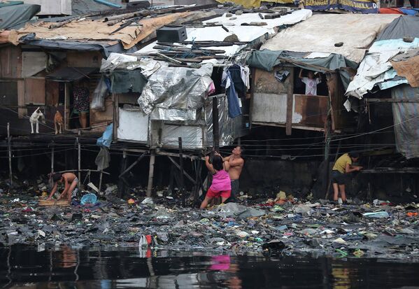 Жители города Манила, Филлипины, у своих жилищ во время тайфуна Раммасун