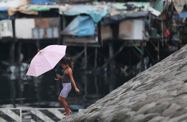 Девочка с зонтиком в городе Манила во время тайфуна Раммасун