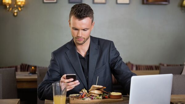 Молодой человек с мобильным телефоном во время обеда