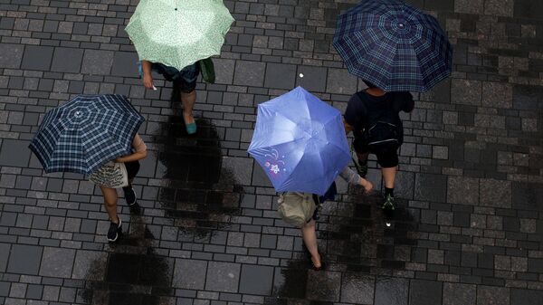 Люди с зонтами на улице Пекина. 16 июля 2014