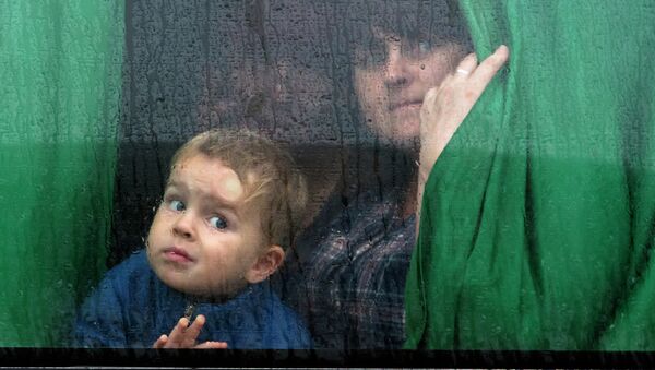Женщина с ребенком в автобусе с беженцами, архивное фото