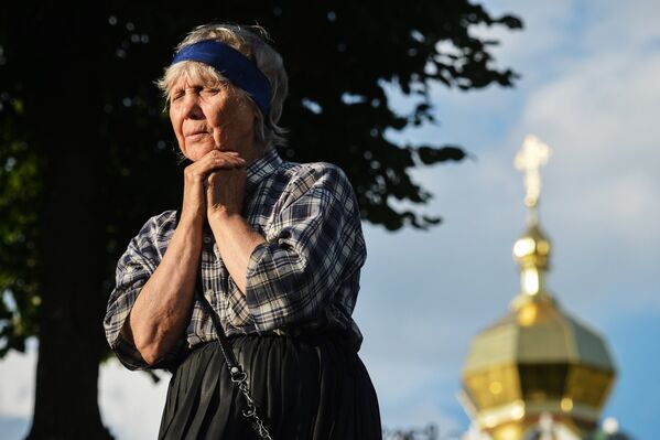 Верующая молится у Троице-Сергиевой лавры в городе Сергиевом Посаде Московской области