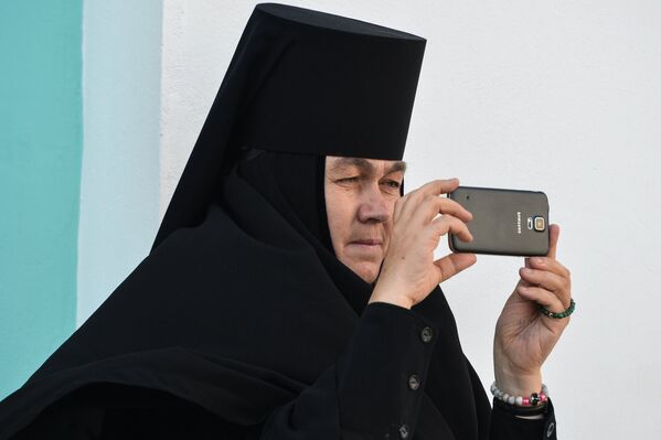 Монахиня фотографирует на мобильный телефон богослужение в Троице-Сергиевой лавре в городе Сергиевом Посаде