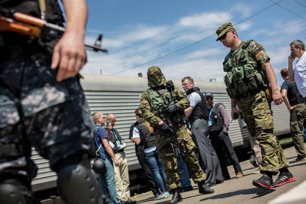 Сотрудники миссии ОБСЕ на станции города Торез перед отправкой в Донецк поезда с пятью рефрижераторными вагонами с телами погибших в авиакатастрофе малайзийского Boeing 777