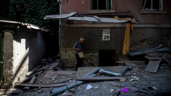 Мужчина спускается в подвал дома, частично разрушенного в результате попадания снаряда во время артиллерийского обстрела Луганска украинскими силовиками