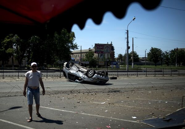 Перевернутый автомобиль на одной из улиц города, поврежденный в результате артиллерийского обстрела Луганска украинскими силовиками