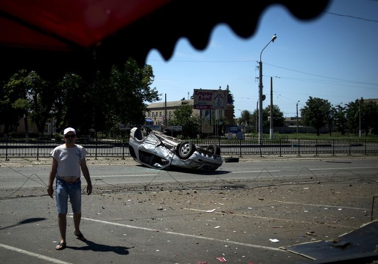 Перевернутый автомобиль на одной из улиц города, поврежденный в результате артиллерийского обстрела Луганска украинскими силовиками