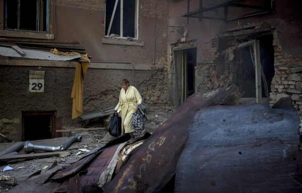 Женщина во дворе разрушенного артиллерийским обстрелом дома в Луганске