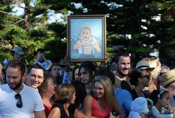Поклонники держат картину с изображенным на ней принцем Джорджем