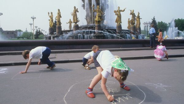 Дети рисуют мелом на асфальте у фонтана Дружба народов