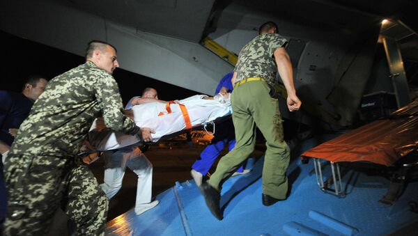 Российские военные помогают погрузить раненого украинского военнослужащего в медицинский самолет для отправки из России на Украину.
