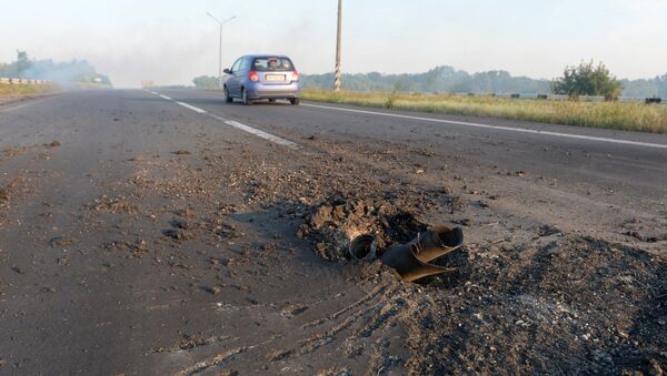 Снаряд от реактивной системы залпового огня Град, выпущенный украинской армией, в полотне дороги на въезде в Донецк