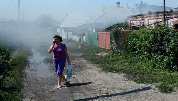 Люди у разрушенных и сгоревших во время артиллерийского обстрела украинской армией домов на окраине Донецка