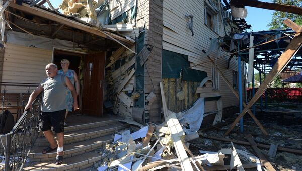 Местные жители выходят из дома, пострадавшего во время ракетно-минометного обстрела Горловки в Донецкой области